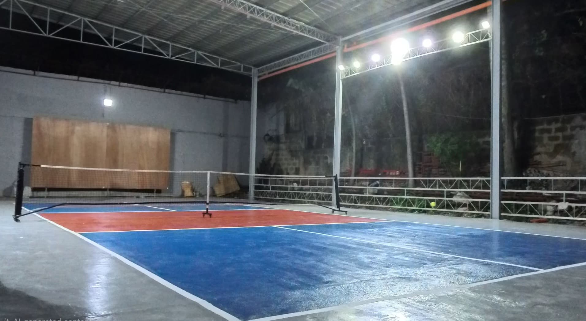 Court 1 — a freshly painted blue and maroon pickleball court under the venue's covered roof