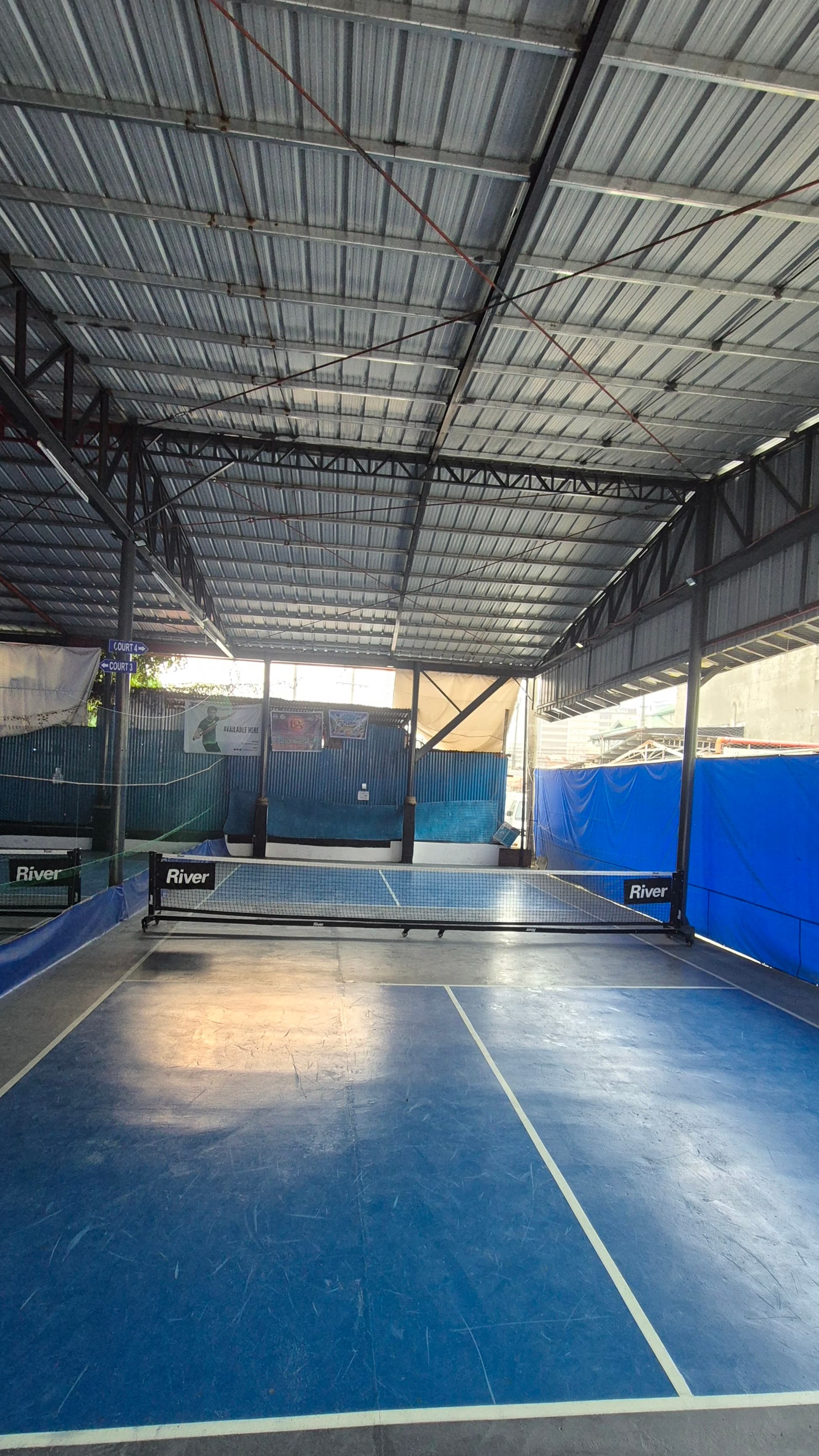 Court 4 — blue pickleball court under the covered steel-roofed pavilion